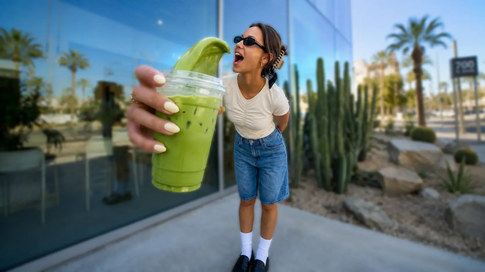 Woman and green drink kept sharp against the same blurred cafe setting.