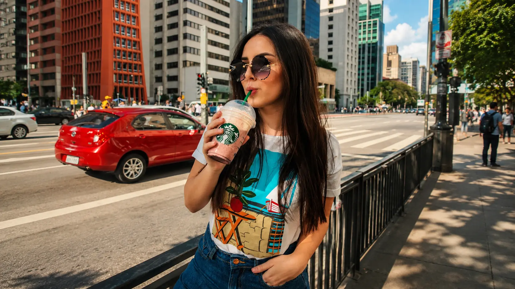 Woman drinking on a busy city sidewalk before background blur.