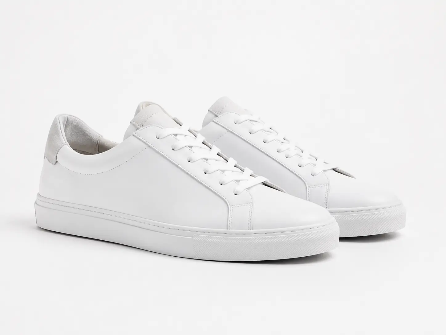White sneakers grounded by a soft AI-generated product shadow.
